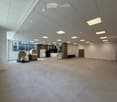 large open space, tiled floor, white walls, ceiling with recessed lighting, large windows, staircase, storage boxes