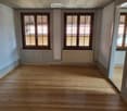 empty room, hardwood floors, two windows, baseboards, radiators, open door