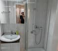 modern bathroom with white sink, shower, cabinet, and tiled walls and floor