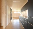 wooden wall, wooden floor, open kitchen, sink, black cabinets, white doors, open doors, wooden stairs