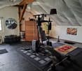 Home gym with weight rack, bench press, mirror, plant, rug, workout mats, dumbbells, lamp