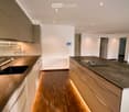 Modern kitchen with two countertops, kitchen island, oven, sink, cabinets, hardwood floors, recessed lighting, doors