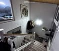 Wooden staircase, white handrail, wooden steps, framed picture on wall, window, closet, table with various items