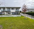 Modern white two-story house, glass balconies, concrete front yard, large green lawn
