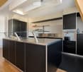 modern kitchen, central island, stainless steel countertop, black cabinets, glass table top, built-in oven