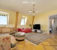 yellow walls, wooden floor, large couch, TV, center table, windows, radiator, lamp