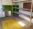 Storage room with yellow floor, two wooden shelves, white door, and green-painted wall