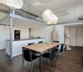 dining area with wooden table and black chairs, kitchen, glass railings