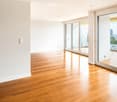 Unfurnished Room. Empty room with wooden flooring, white walls, and large glass sliding doors leading to a balcony.