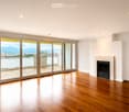 Unfurnished Room. Empty room with wooden flooring, large sliding glass doors leading to a balcony, fireplace, and scenic mountain view.