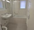 Clean bathroom with tiled walls and floor, bathtub, shower, sink, and toilet.