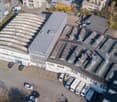 Large building with multiple floors, solar panels on the roof, multiple cars parked in front