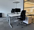 modern office with white desks, black chairs, computer monitors, and a glass wall