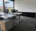 Office room with two desks, computer monitors, chairs, cabinets, and a view of the outside.
