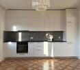 modern kitchen with white cabinets, black countertops, wooden floor, integrated oven and dishwasher, chandelier