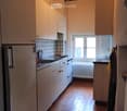 kitchen with white cabinets, tiled floor, refrigerator, sink, oven, window, radiator