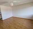 empty room, wooden floor, white walls, large window, kitchen area