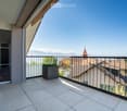 Balcony with tiled floor, black railing, potted plant, glass doors, view of houses and mountains