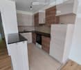 modern kitchen with wooden cabinets, black countertops, white ceiling, wooden floor, built-in oven, sink, faucet
