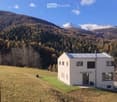 House. Modern white house with a flat roof, set in a mountainous landscape with snow-capped peaks.