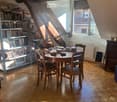 Wooden floor, wooden table and chairs, bookshelves, lamp, books, speaker, radiator, window