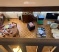 wooden floor, round table, chairs, ottoman, couch, books, TV, speaker, radiator, plant