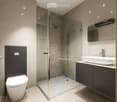 Modern bathroom with a glass shower enclosure, white toilet, and a white sink with a faucet.