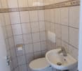 Bathroom. Small bathroom with white tiles, a toilet, a sink, and a wall-mounted soap dispenser.