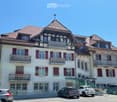 3 story building, white walls, red shutters, brown roof, balconies, parking area