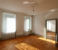 Empty room with parquet floors, white walls, white curtains, glass windows, radiator, ceiling lamp