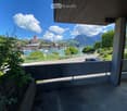 Balcony / Terrace. Balcony with a view of a lake, boats, and distant mountains under a partly cloudy sky.