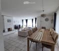 Furnished Room. Bright living and dining area with a sofa, dining table, chairs, television, fireplace, and decorative picture frames.