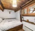 Cozy attic bedroom with wooden beams, a single bed, nightstand, and built-in wooden cabinetry.