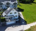 Aerial view of a modern two-story house with solar panels, garage, and spacious lawn.
