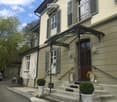 2 story house, beige walls, gray shutters, brown door, black railing, 3 steps, 3 potted plants