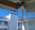 Balcony with glass railing, overlooking a modern building with white facade and multiple windows.