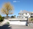 Two-story house with a garage, raised ground floor, and a balcony overlooking the street.