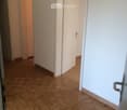 Empty hallway with wooden herringbone flooring, white walls, and two closed doors.