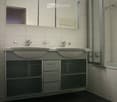 Modern bathroom with double sink vanity, mirrored cabinet, bathtub, and toilet.