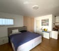 Modern bedroom with a large bed, nightstands, a painting, and a round ceiling light.