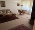 Living room with a sofa, coffee table, dining area with table and chairs, and decorative items.