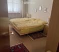 Cozy bedroom with a double bed, nightstands, lamps, a small chair, and decorative rugs.