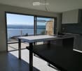 Modern kitchen with a central island, sleek dark cabinets, and expansive windows offering a scenic lake view.