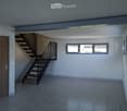 Empty hallway with tiled floor, wooden door, staircase leading upwards, and large windows letting in natural light.