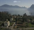 Aerial view of a residential area with houses, mountains, and a lake in the background.