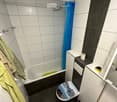 Modern bathroom with a bathtub, toilet, towel, toilet paper, shower curtain, and a showerhead.
