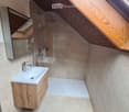 Bathroom with wooden ceiling, white sink, wooden cabinet, glass shower enclosure, mirror, and ceiling lights