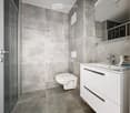 Modern bathroom with grey tiled walls and floor, white toilet, white sink with modern faucet, and a glass-enclosed shower area.
