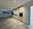 Modern kitchen with light-colored cabinets, stainless steel oven, and granite tile flooring.