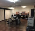 office with wooden floor, multiple desks, cabinets, shelves, office equipment